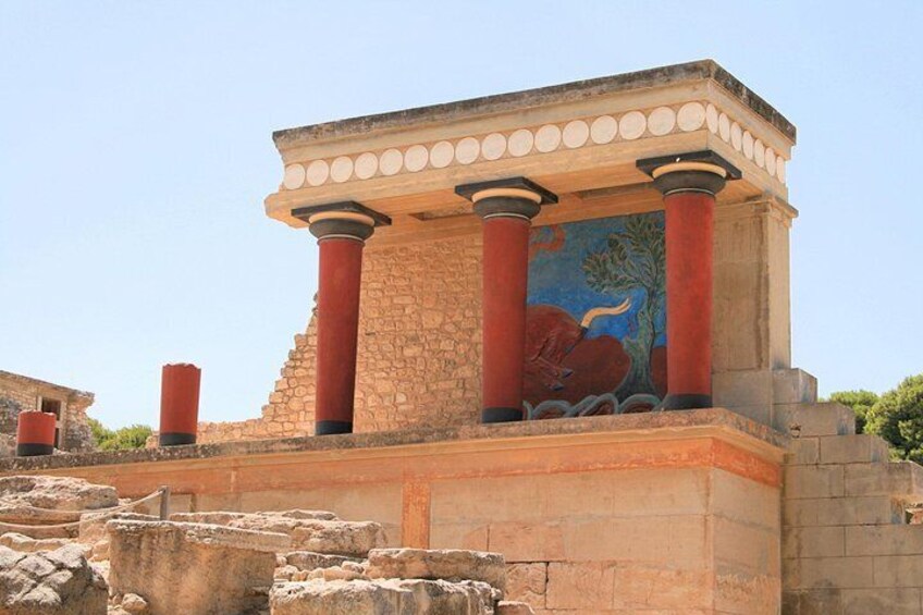 An ancient structure with red columns and a mural depicting a bull. 1
