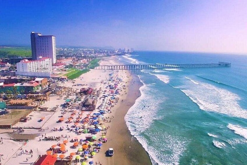 Una spiaggia con ombrelloni, un molo e degli edifici. 2