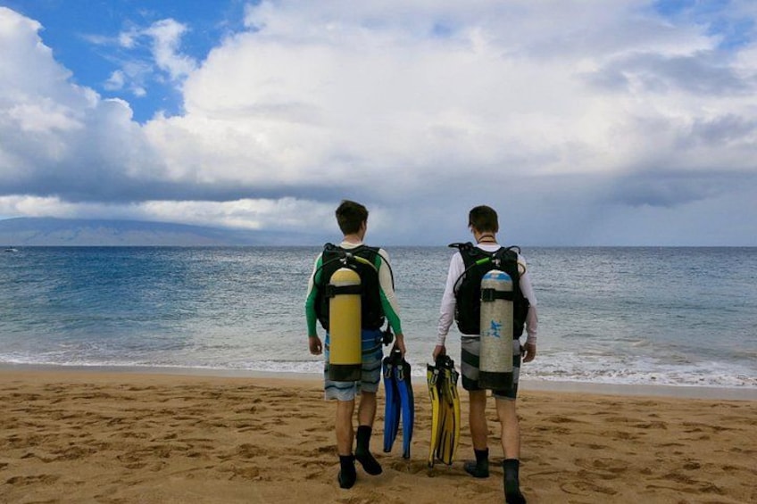 Two people on a beach with scuba gear, ocean in the background. 3