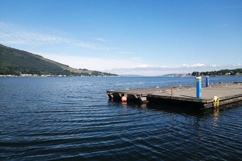 A calm lake with a pier extending into the water, surrounded by hills and a clear sky. 3
