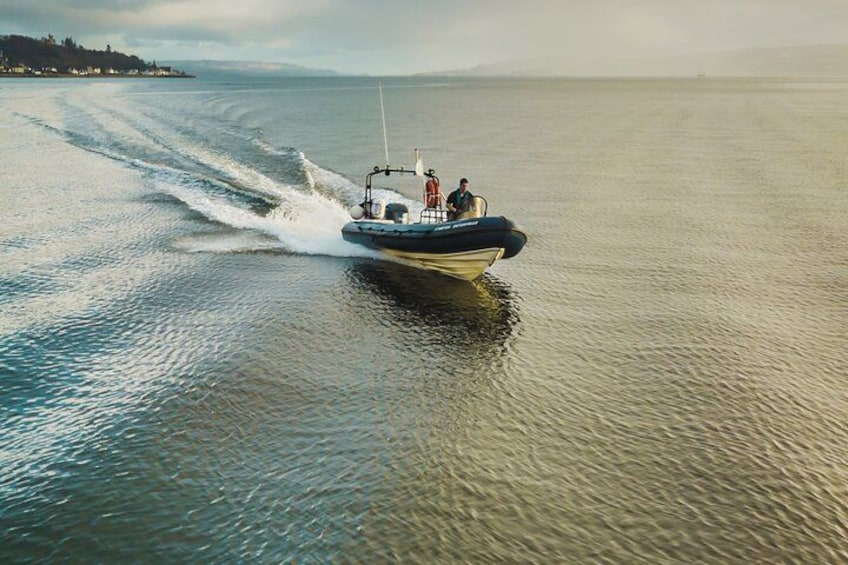 A speedboat with two people on board, moving across a calm body of water. 2