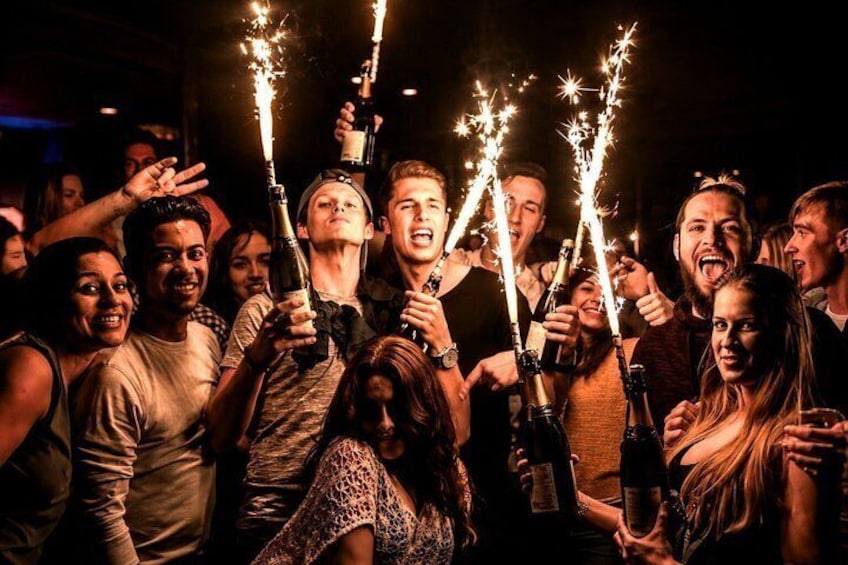 En grupp människor som håller i champagneflaskor med små, glittrande bengaliska eldar. 4