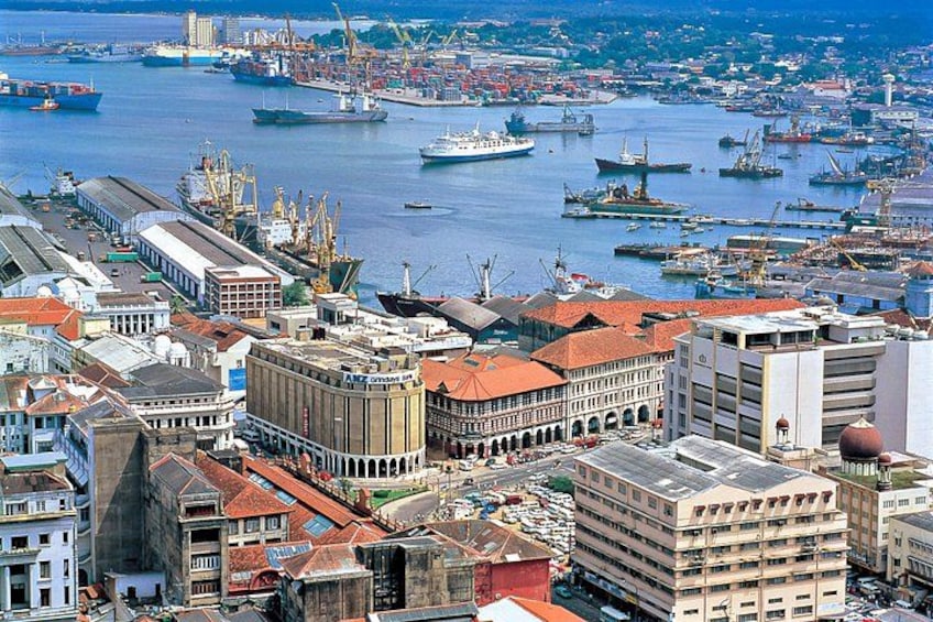 Eine Küstenstadt mit einem Hafen voller Schiffe, Industriegebäuden und einem markanten Glockenturm. 1