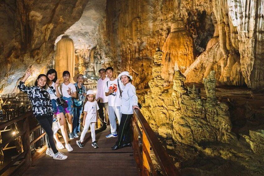 Un gruppo di persone in una grotta con stalattiti e una passerella di legno. 5