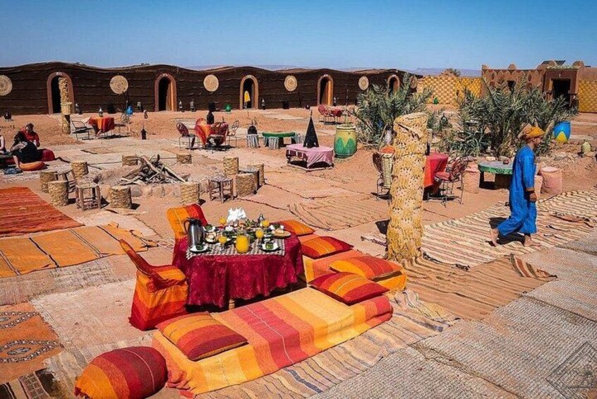 Een woestijnlandschap met traditionele tenten en een gedekte tafel. 1