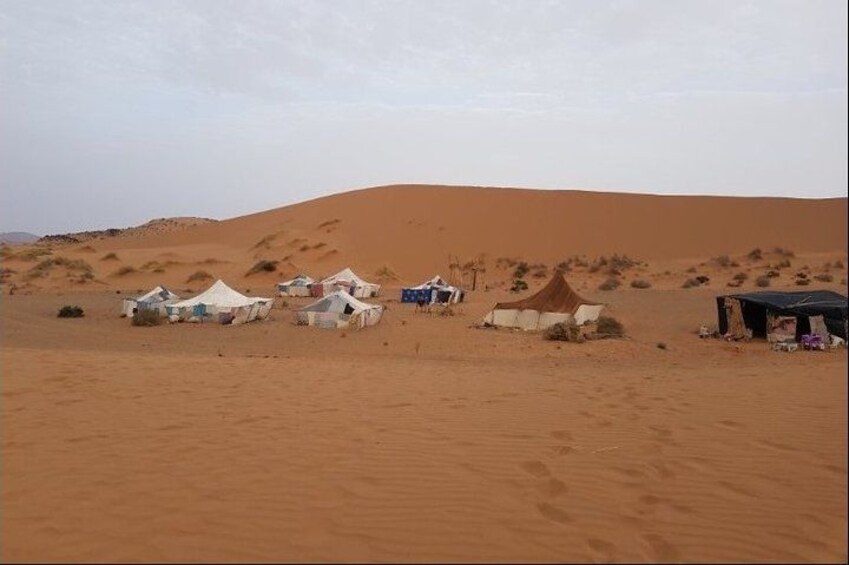 Paisaje desértico con dunas de arena y varias tiendas de campaña. 4