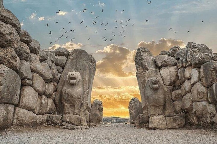 A stone archway with animal faces, birds flying, and a sunset. 5