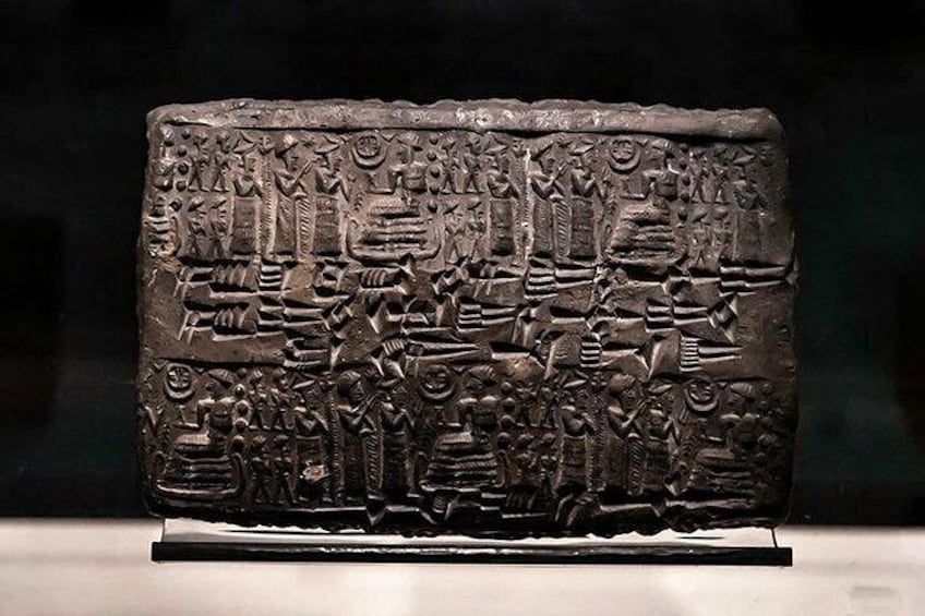 A stone slab with ancient carvings, including figures and symbols. 4
