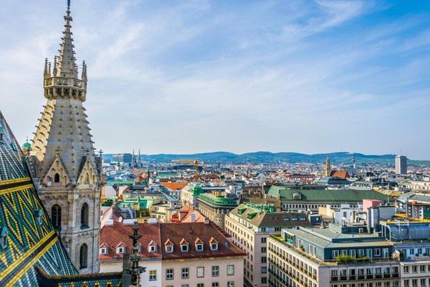 A cityscape with a prominent church spire, a variety of buildings, and a distant mountain range. 4