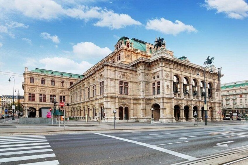 A historic building with classical architecture, a crosswalk, and a clear blue sky. 3