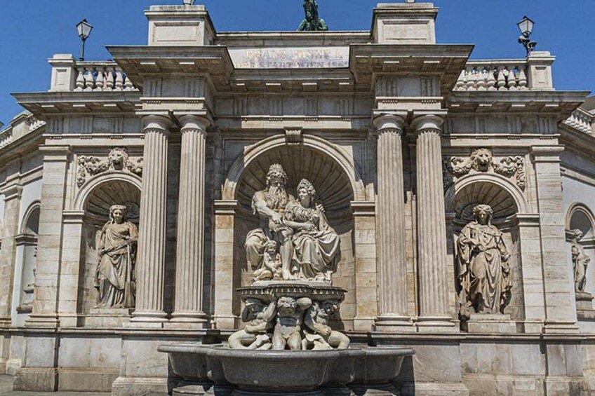 A classical building facade with columns, statues, and a central relief sculpture. 2