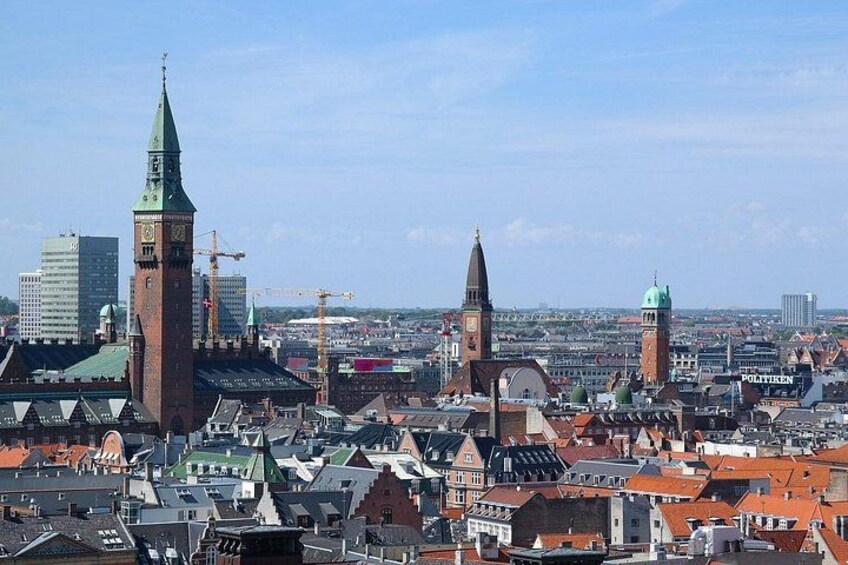 Un paisaje urbano con edificios históricos, una imponente torre del reloj y grúas de construcción al fondo. 5