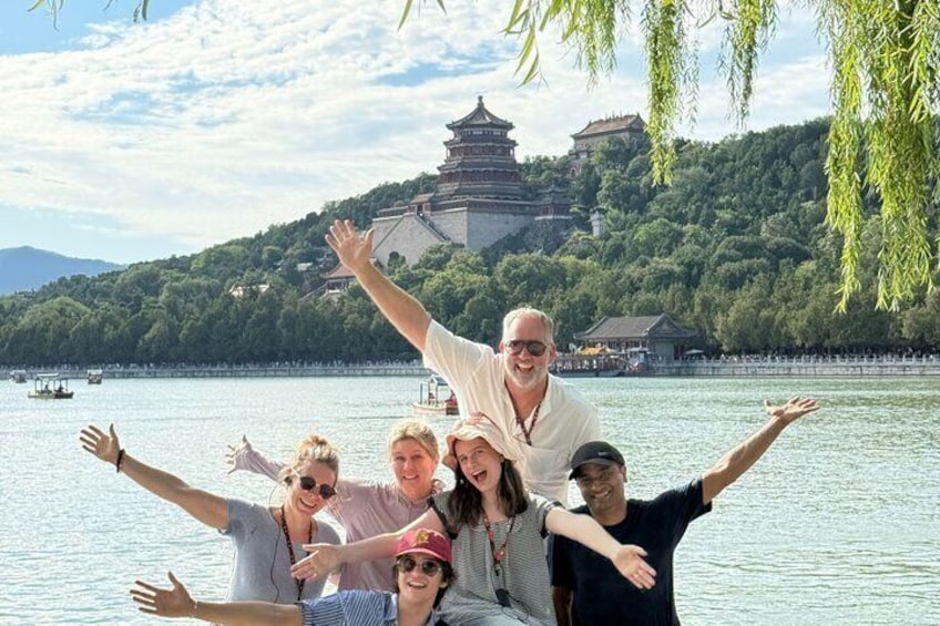 A group of people by a lake with a traditional pagoda in the background. 1