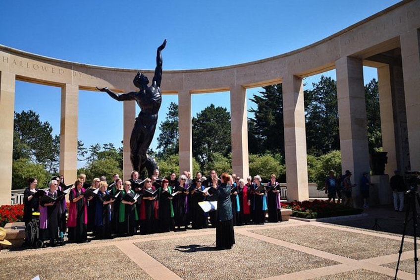 A group of people in front of a monument with a statue of a person in a dynamic pose. 3