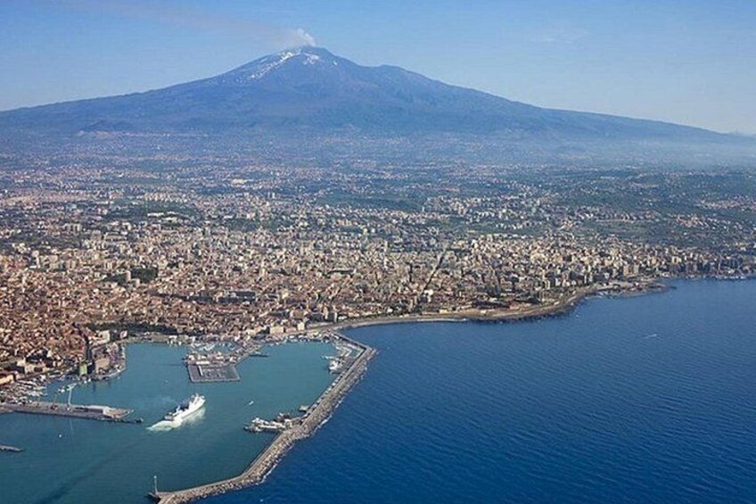 A coastal city with a large body of water, a marina, and a prominent mountain in the background. 1