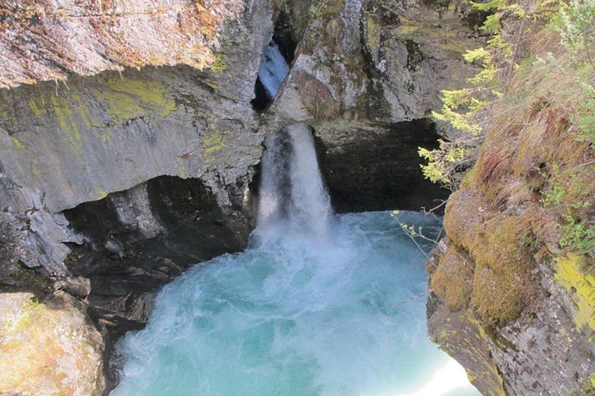 A waterfall cascading into a pool surrounded by rocky cliffs. 1