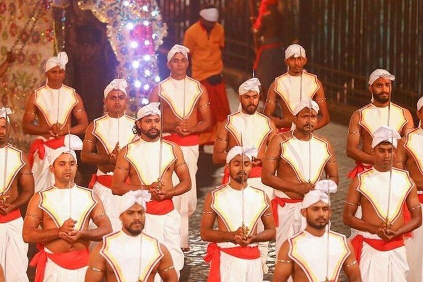 A group of men in traditional white and red attire standing in formation. 3