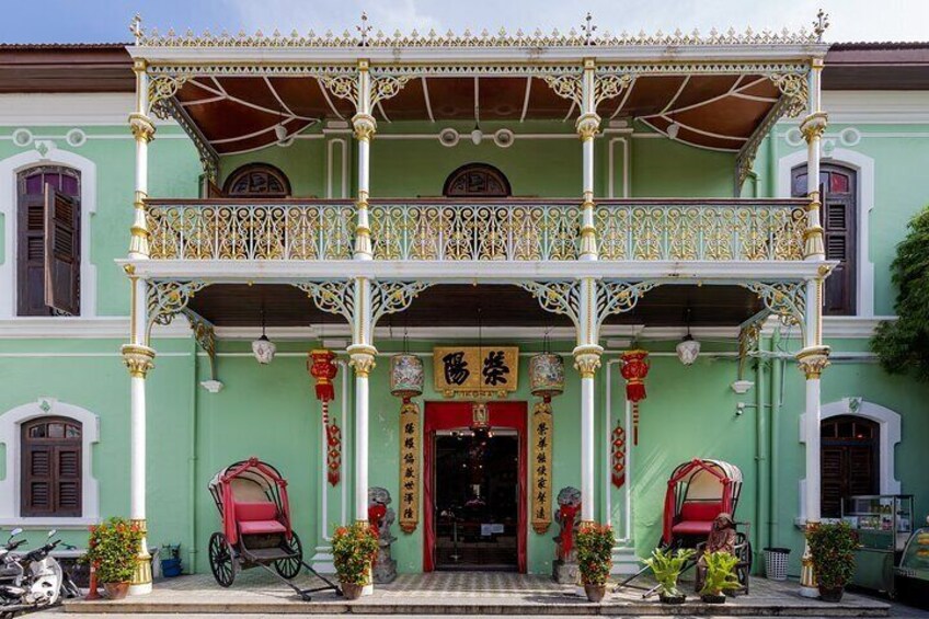 A traditional building with ornate balconies, a red entrance, and potted plants. 1