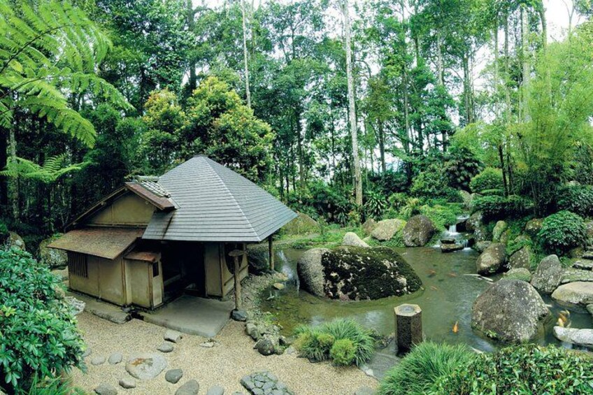 A traditional Japanese house surrounded by a natural landscape with a stream and rocks. 5