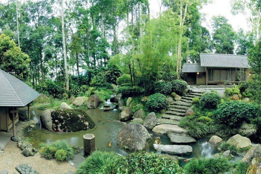 A traditional Japanese garden with a koi pond, stepping stones, and a wooden structure. 4