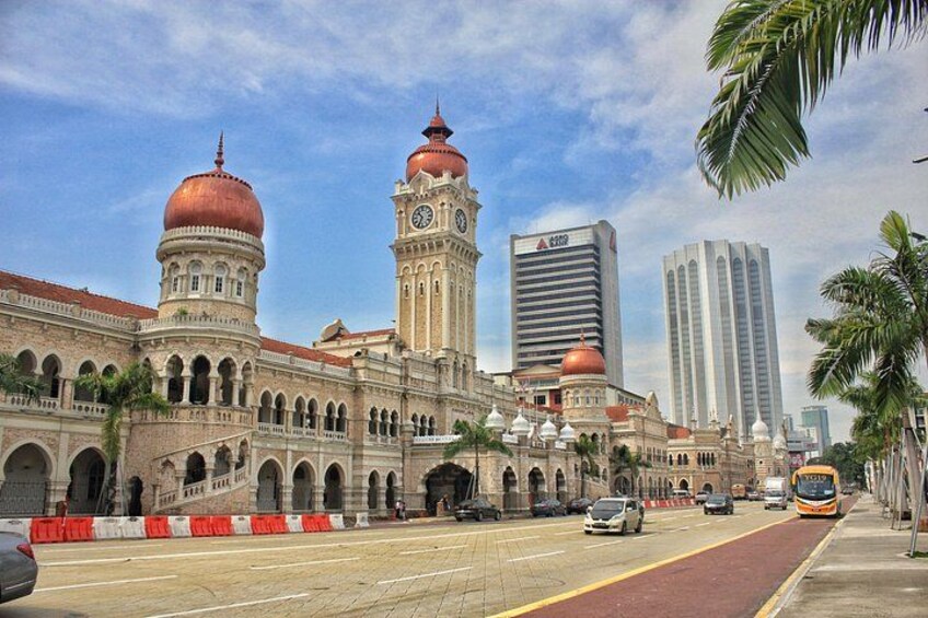 A historic building with domed towers, a clock tower, and modern high-rise buildings in the background. 2