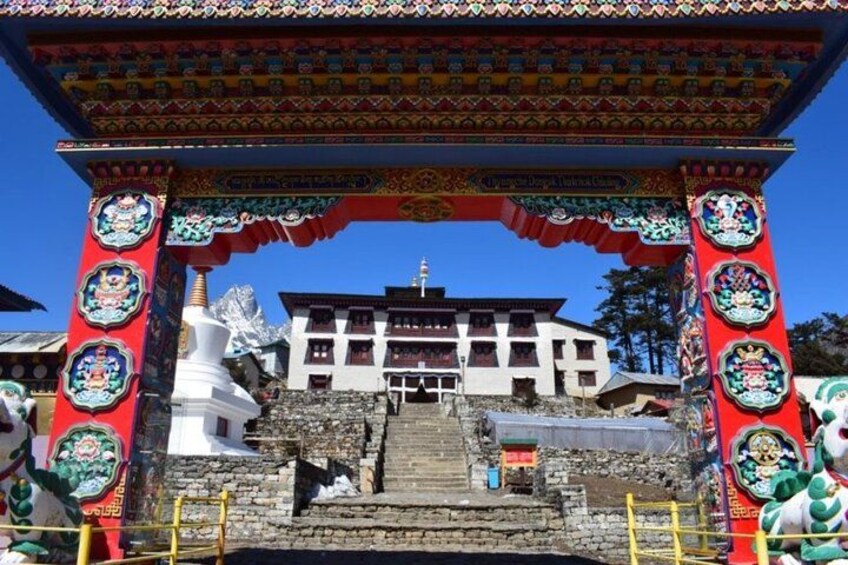 En traditionell tibetansk byggnad med en färgstark entrébåge, en vit stupa och en trappa som leder upp till entrén. 2