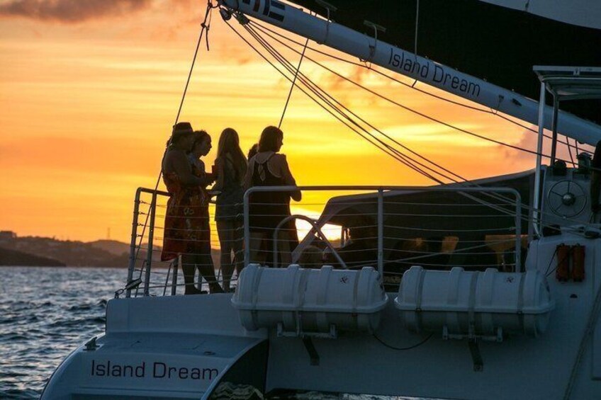 Ein Segelboot namens 'Island Dream' mit Personen an Deck bei Sonnenuntergang. 3