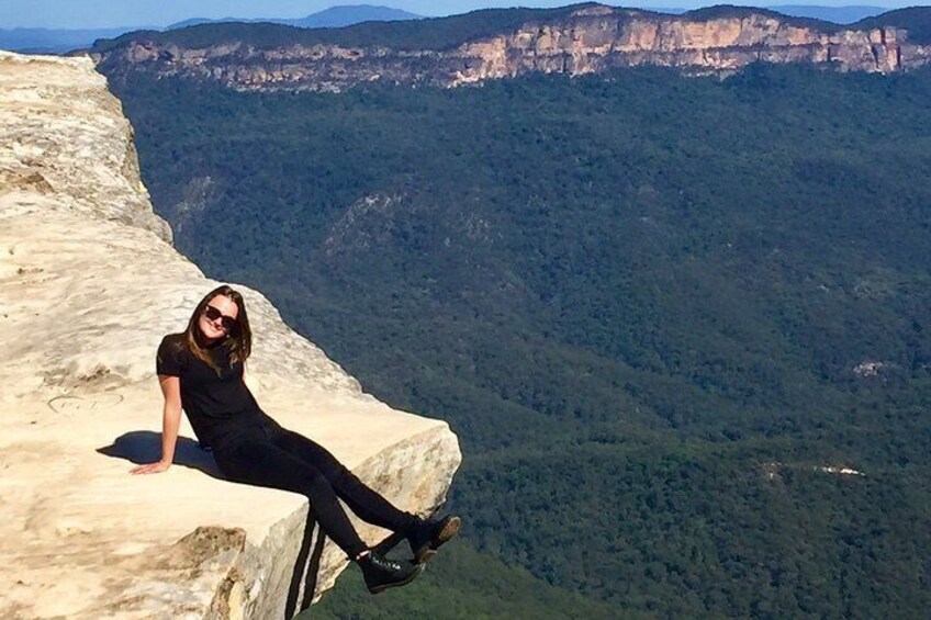 A person sitting on a cliff edge with a vast canyon in the background. 2