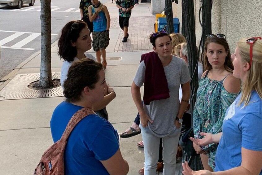A group of people standing on a sidewalk, engaged in conversation. 4