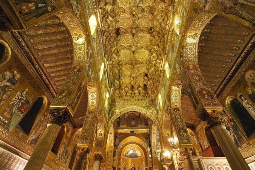 Een rijk versierd interieur met ingewikkelde gouden decoraties, kolommen en een centrale boog. 1
