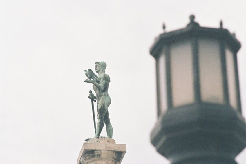A statue of a man holding a lyre, a classical sculpture, and a street lamp in the foreground. 3