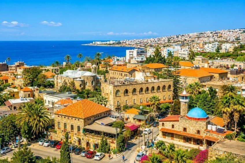 Un paisaje urbano costero con edificios históricos, una torre destacada y un mar azul y despejado. 3