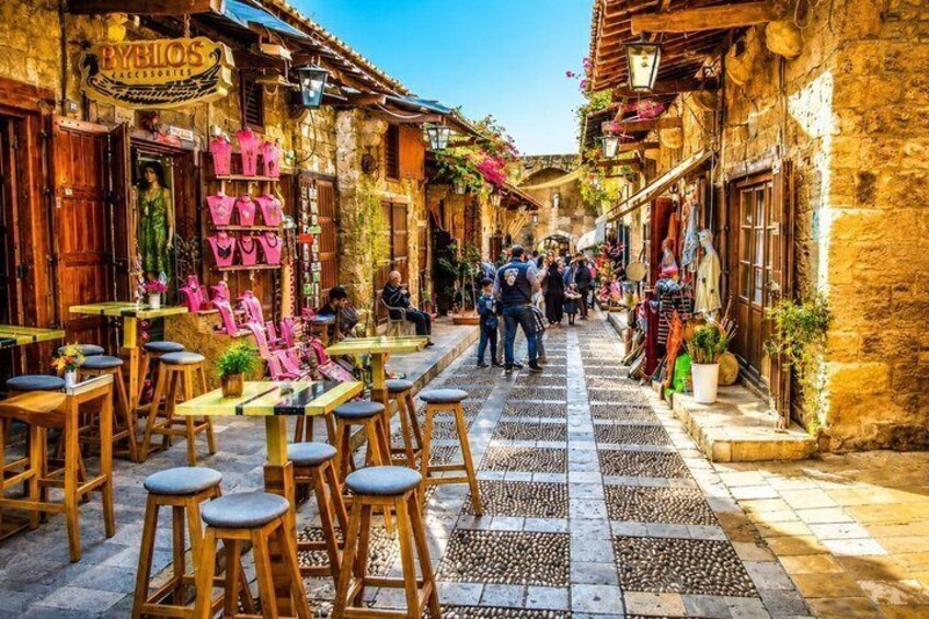Una calle estrecha con tiendas, mesas al aire libre y gente caminando. 2