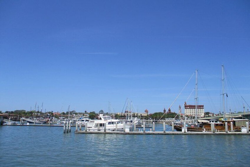 Un puerto deportivo con barcos amarrados, cielo azul despejado y un edificio al fondo. 2