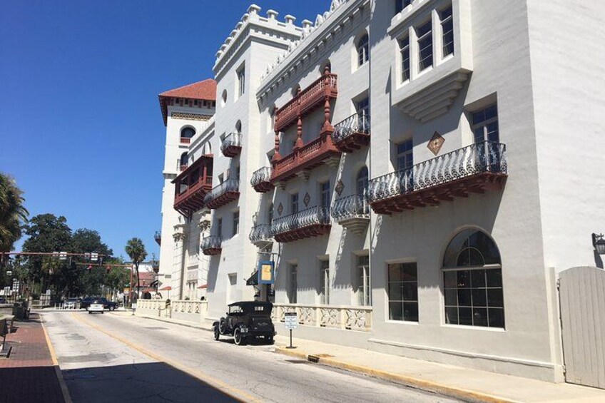 Un edificio blanco con balcones rojos y un cielo azul despejado. 4