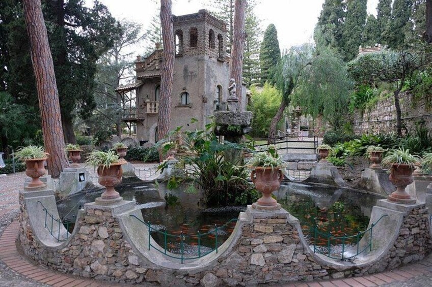 Ein Garten mit einem Brunnen, Steinarchitektur und einem Gebäude im Hintergrund. 2