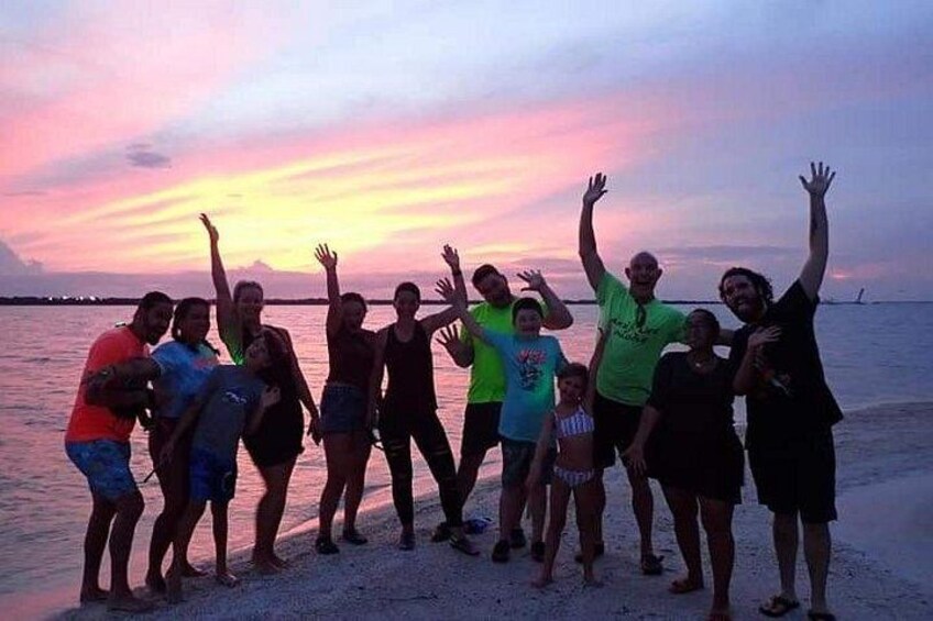A group of people standing on a beach at sunset. 2