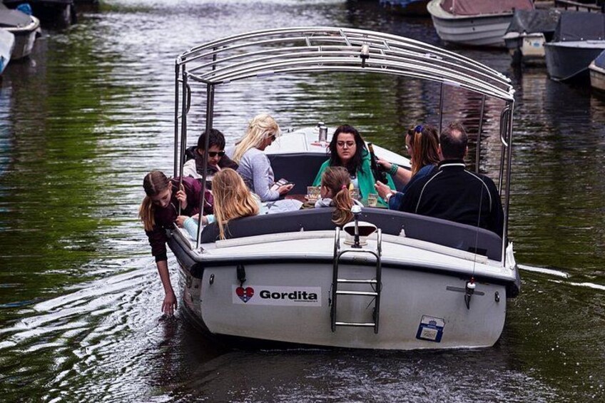 Una piccola imbarcazione con persone a bordo, ormeggiata in un porto turistico. 5