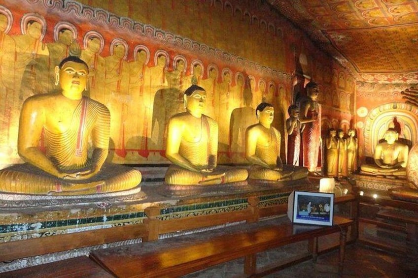 L’intérieur d’un temple, avec de grandes statues de Bouddha, des sculptures complexes ornant les murs et une plaque d’information encadrée. 3