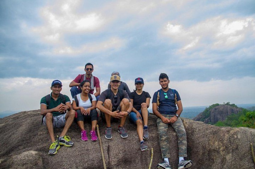 Un groupe de personnes est assis sur une grande formation rocheuse, avec un paysage montagneux en arrière-plan. 3