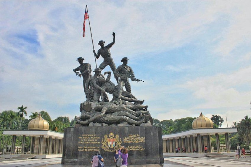 A statue of soldiers on a hill with a flag, surrounded by buildings and greenery. 2