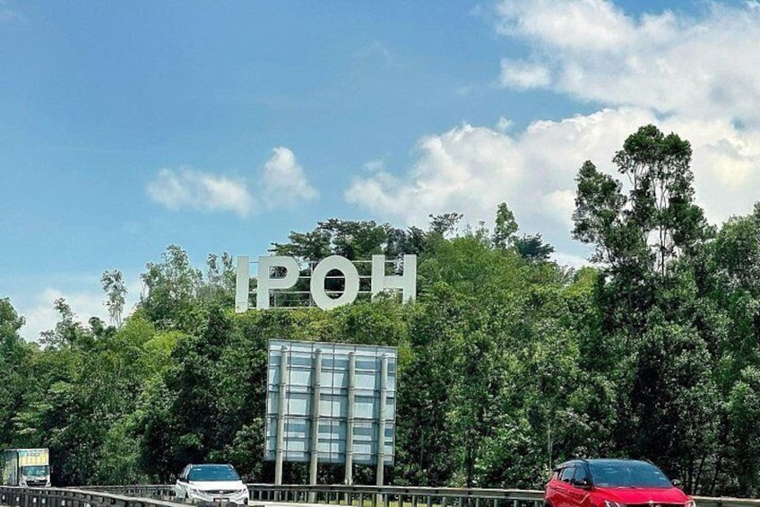 Una carretera con un edificio grande al fondo, rodeado de árboles. 1