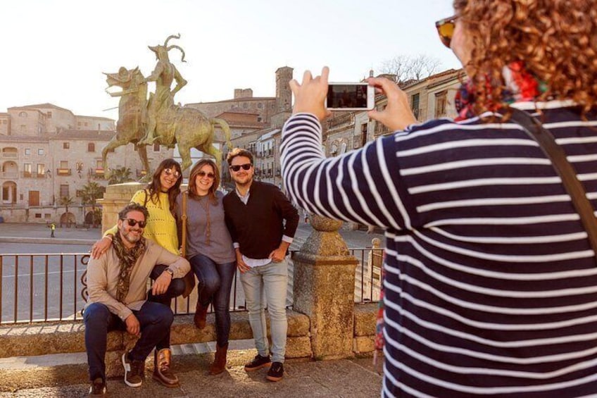 A group of people posing for a photo in front of a statue. 4