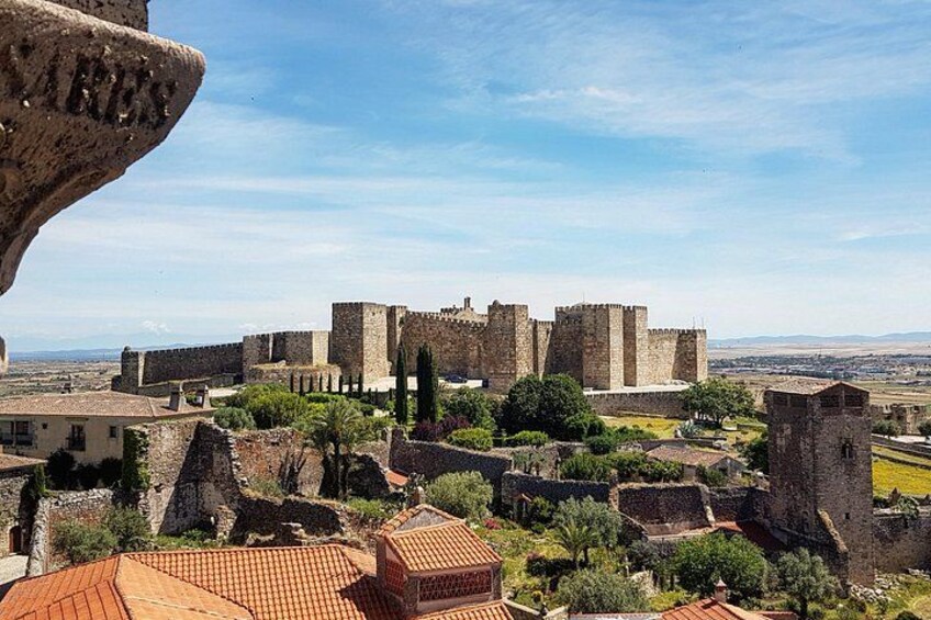 A historic castle with surrounding ruins and a clear sky. 2
