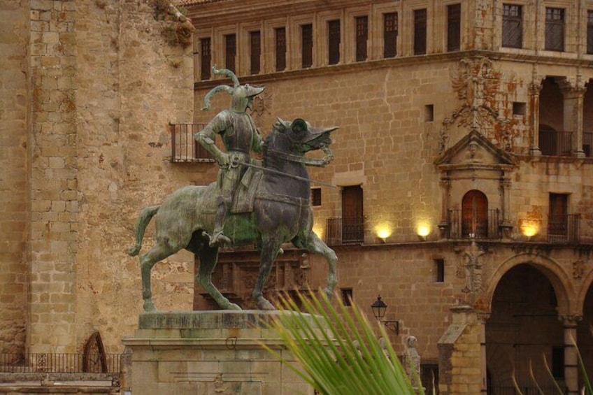 A statue of a knight on horseback in front of a historic building with balconies and arches. 1