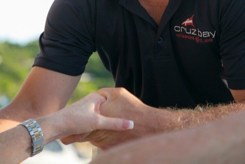 A person wearing a black polo shirt with the logo "Cruzbay Watersports St. John". 1