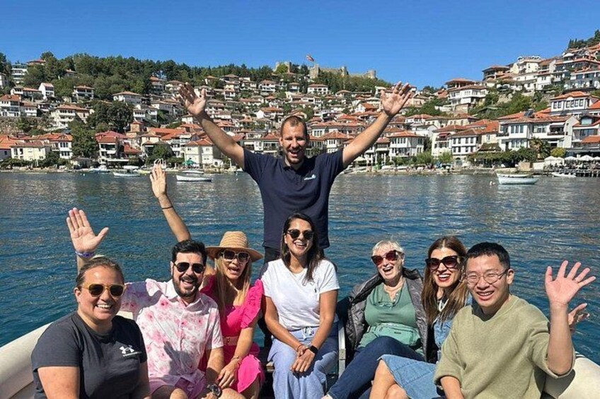 A group of people on a boat with a lake and houses in the background. 3