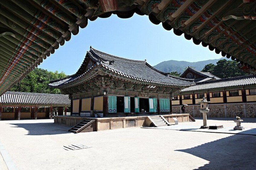 Ein traditionelles koreanisches Gebäude mit einem Ziegeldach, einem Kieshof und einer Statue. 5