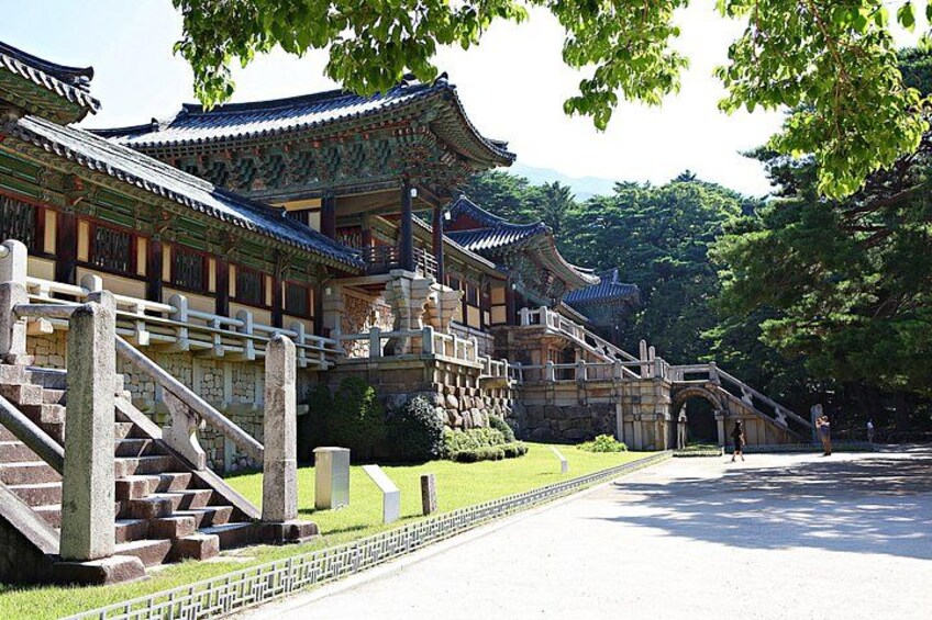 A traditional Korean palace with ornate architecture, a stone staircase, and a well-maintained garden. 4