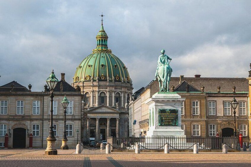 A historic building with a green dome and a statue in front. 4